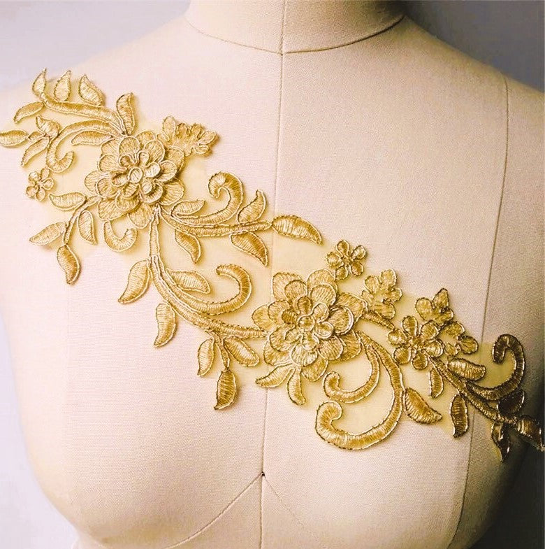 A single gold corded  applique in a trailing floral design embroidered onto organza with a  3D flower near each  end . Displayed across the bodice on a mannequin.