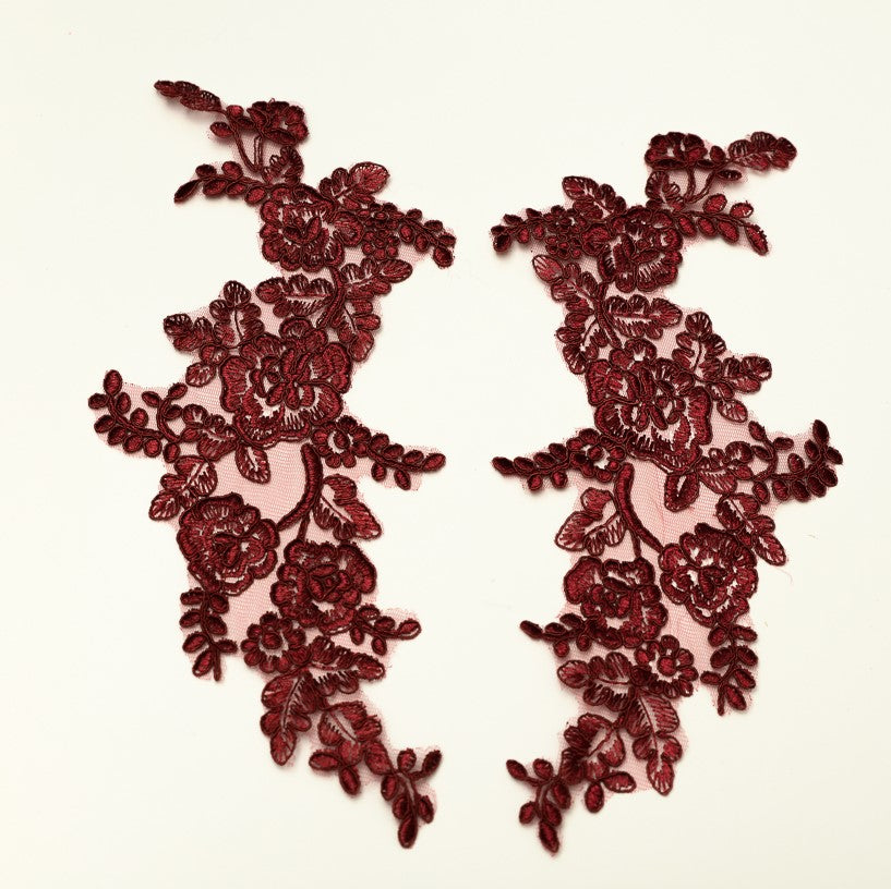 Burgundy embroidered applique pair laying flat on a white background.  The appliques are edged with burgundy cord.