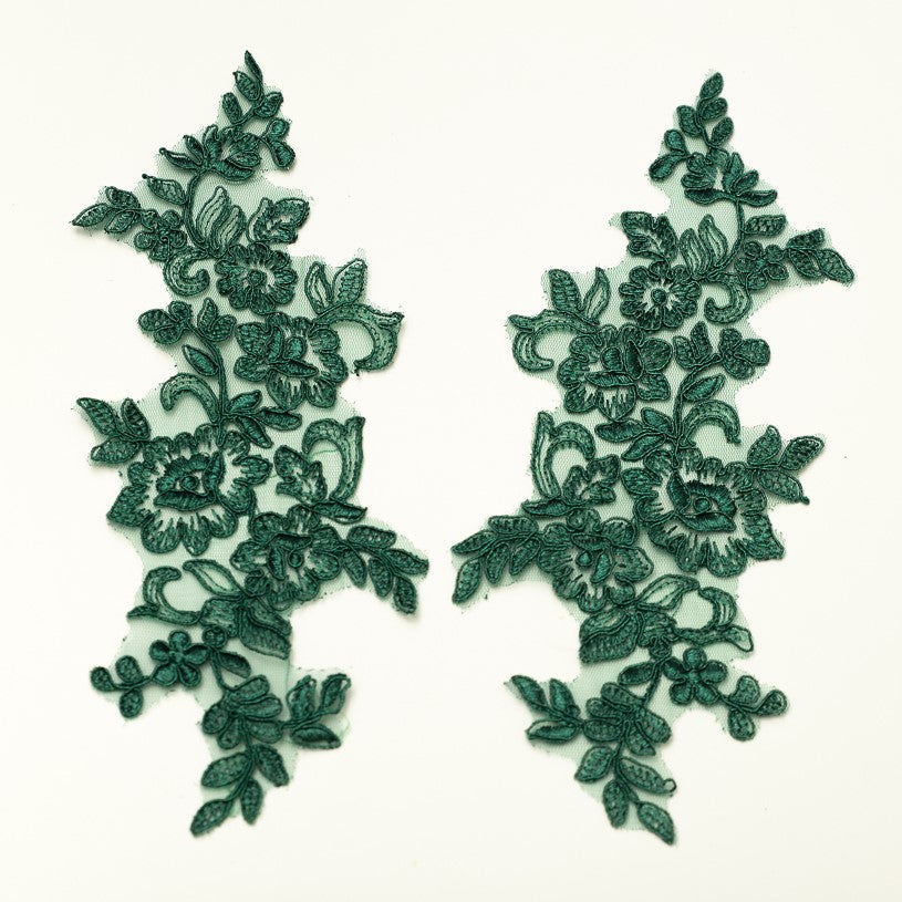 Mirrored pair of dark green corded appliques laying flat on a white background.