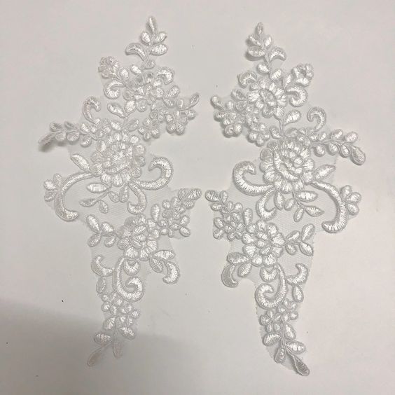 Mirrored pair of light grey corded floral appliques embroidered onto a fine grey net.