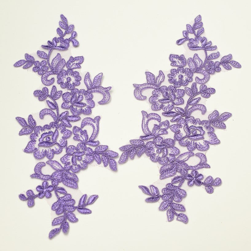 A pretty wisteria purple embroidered floral applique embroidered onto a net backing.  The appliques are laying flat on a white background.