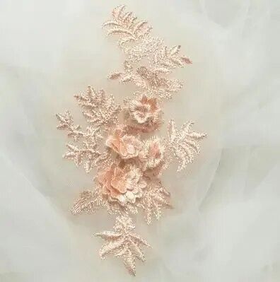 A pretty softly embroidered pale apricot  champagne coloured applique on a fine white net  displayed on  white tulle.