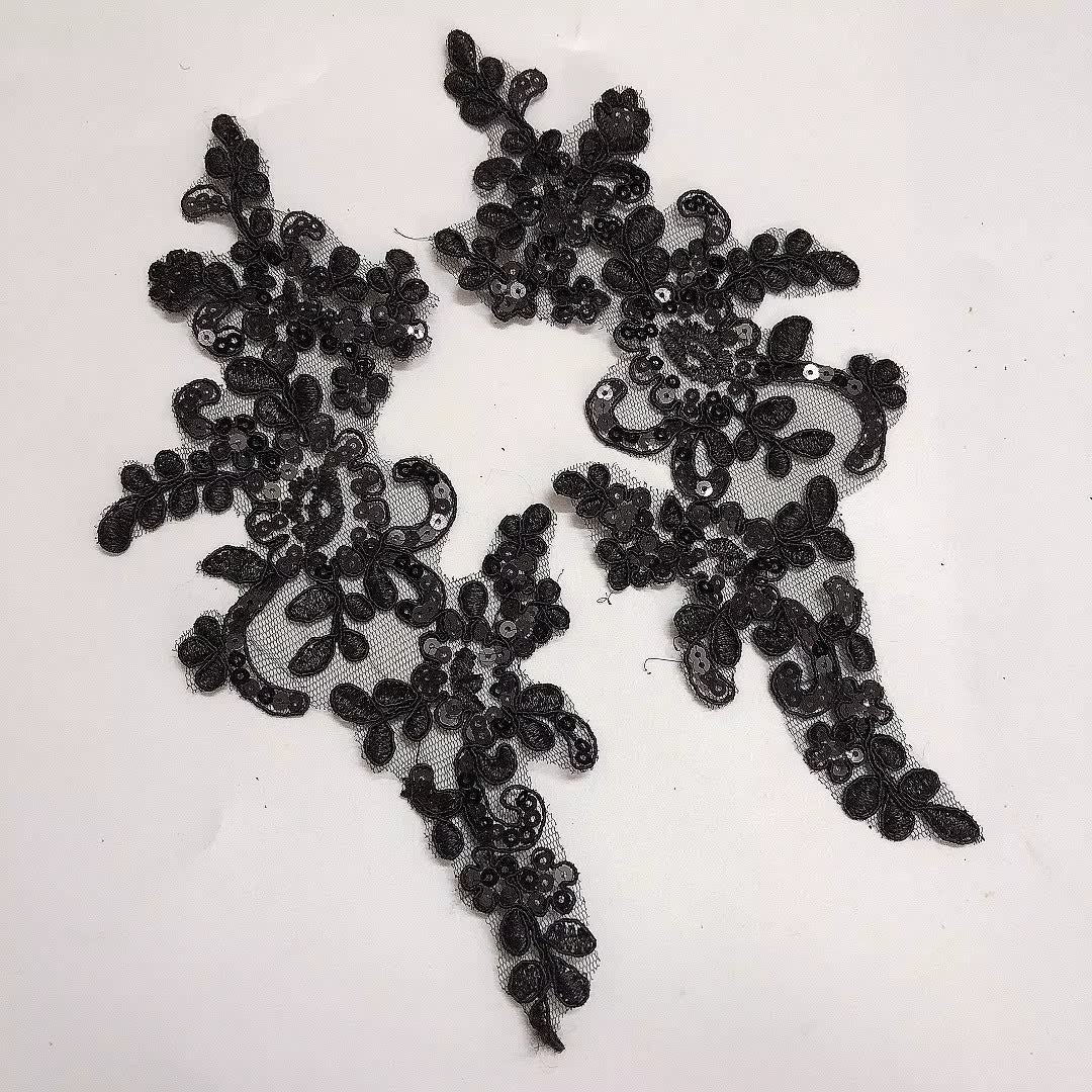A pair of black lace applique patches with floral and scroll patterns, featuring mesh backing and small sequins, laid flat on a white background. 