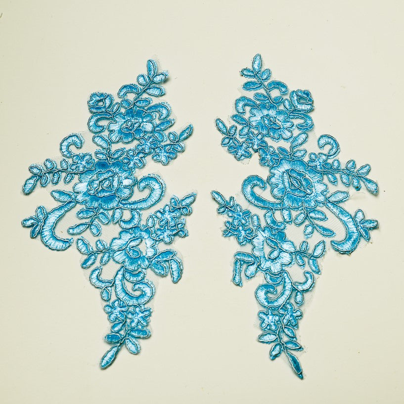 Mirrored pair of turquoise blue floral embroidered appliques .