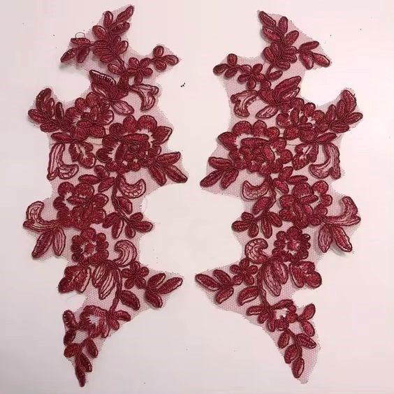 Mirrored pair of burgundy corded appliques.  The appliques are laying flat on a white background.