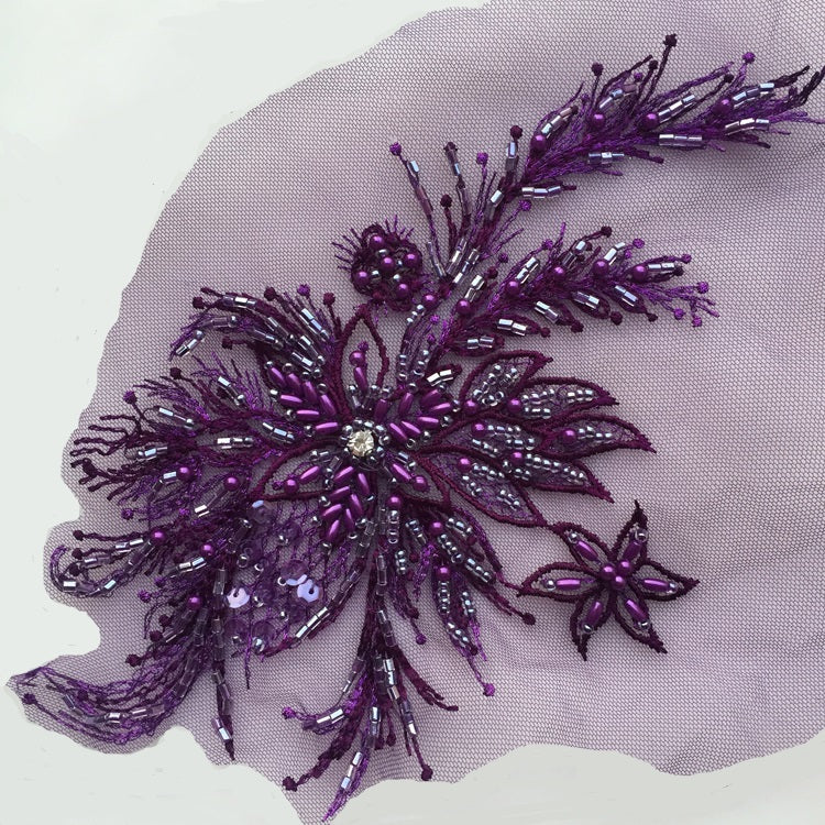 A deep purple beaded applique with a large central beaded flower and sprays of  stems and leaves of purple and clear beads  on purple net. A lovely bodice decoration .