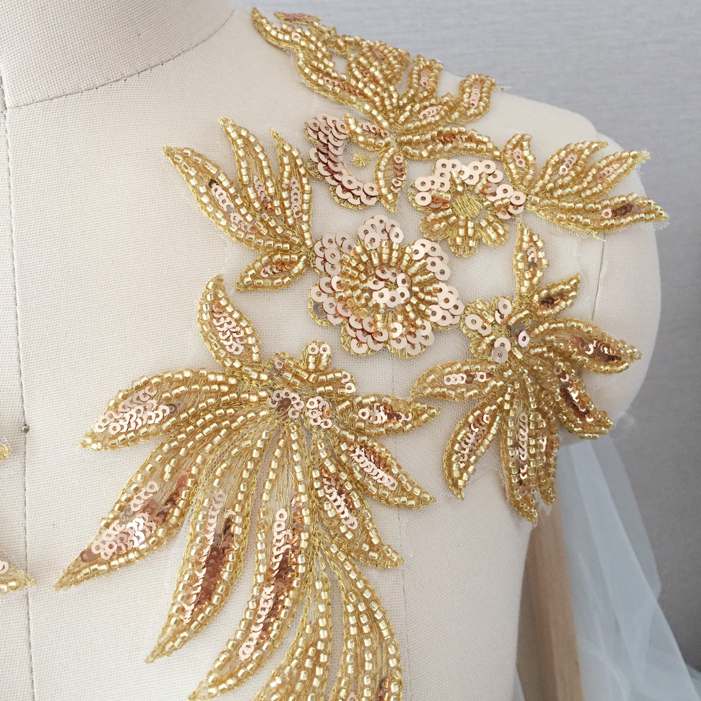 Gold beaded and sequinned flower spray  on the shoulder of a mannequin .