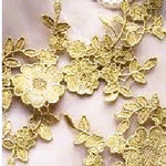 Close up view of old gold venise lace applique showing the floral pattern.