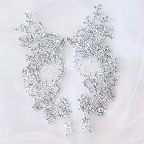 Light floral embroidered and corded lace applique pair with cross hatch design in the centre of the applique laying flat on white net.