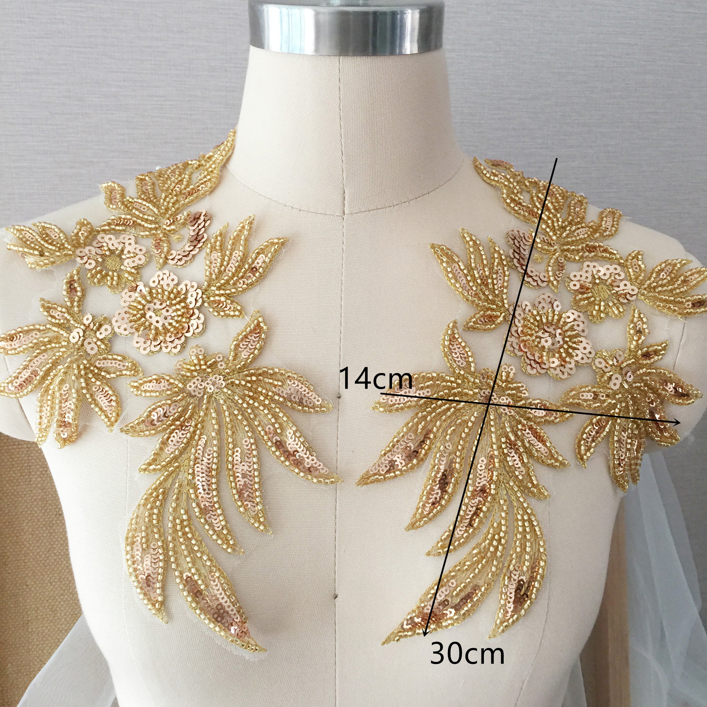 A mirrorred pair of gold beaded and sequinned floral sprays  displayed on the bodice of a mannequin .