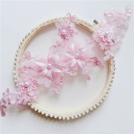 Pink embroidered applique with corded flowers and leaves. Small lace daisies are layered onto three organza 3D flowers . A single pearl decorates each flower centre.
