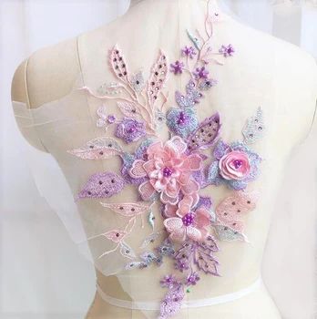Single 3D floral applique in pastel shades of pink, lavender and green. The 3D flowers have pearl centers and sequinned petals. The applique is sprinkled with purple gems and is displayed on a mannequin.