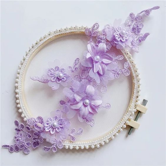 Purple Orchid embroidered applique with corded flowers and leaves. Small lace daisies are layered onto three organza 3D flowers . A single pearl decorates each flower centre.