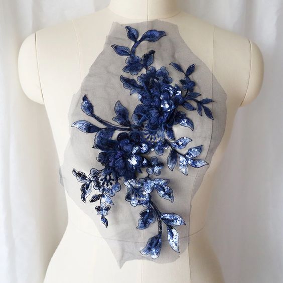 A large royal blue sequinned applique in a floral design  embellished  with 3D flowers  with sequinned petals. The costume applique  is displayed on a mannequin.