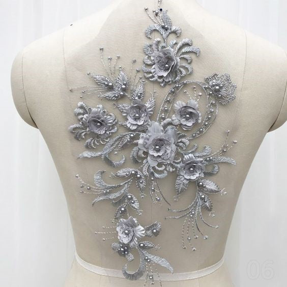 Silver 3D floral applique embroidered onto a net backing.  The flower centres and leaves are embellished with silver pearls.