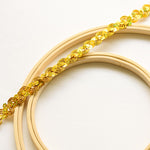 A strand of gold sequinned trim in a wave design . The gold laser hologram sequins reflect blues and greens. 