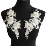 A 3d embroidered floral applique with three  large flowers with rhinestone and pearl centres  displayed on a  mannequin .