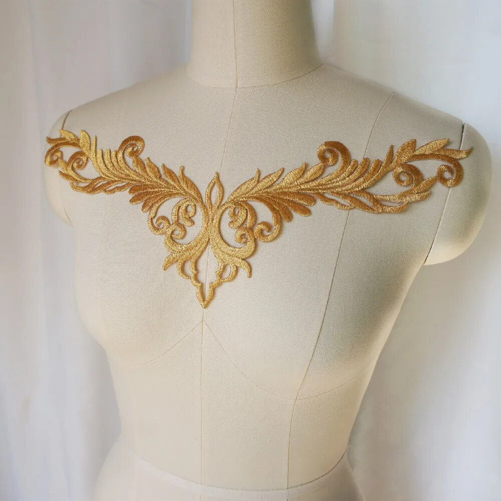 A gold neckline applique in a swirling V shaped design displayed on a mannequin.