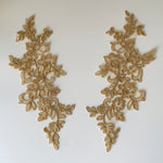 A golden coffee caramel embroidered and corded applique in a floral design laying flat on a white background. 