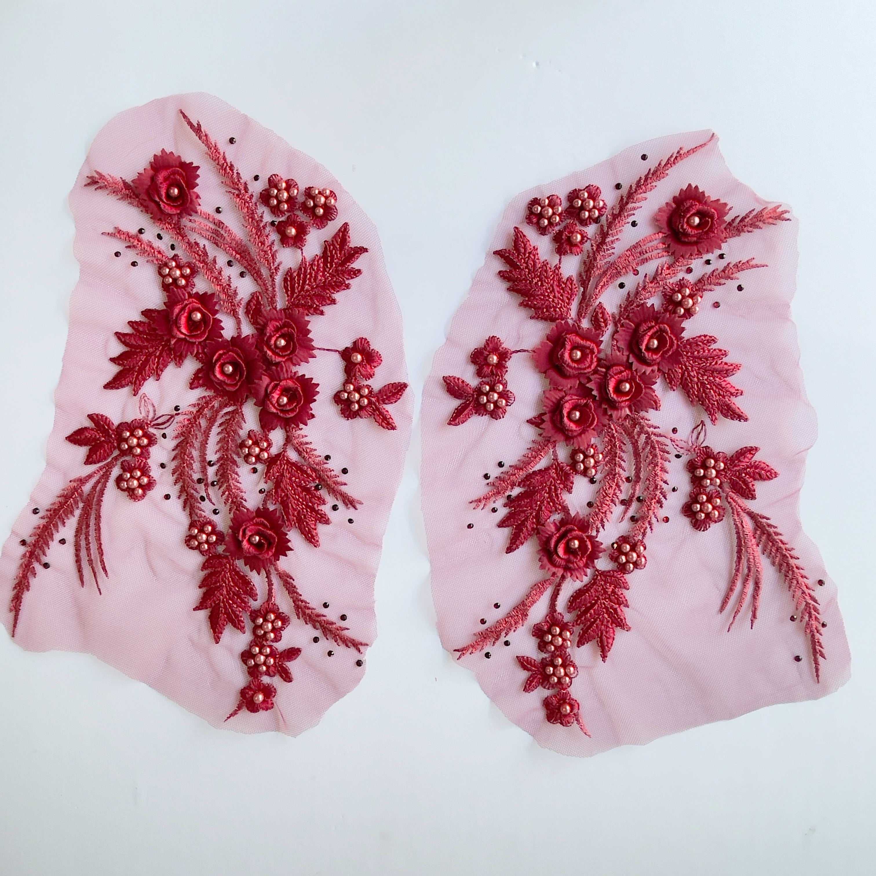 Burgundy mirrored applique pair with lots of texture combining 3D flowers with burgundy pearls,  metallic thread embroidery and a scattering of burgundy gems embroidered onto fine net. 