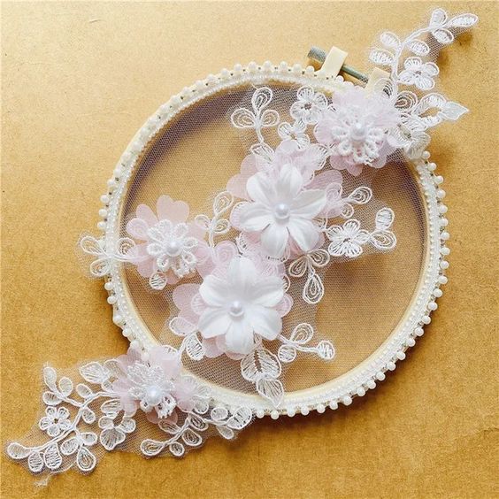 Pink embroidered applique with corded flowers and leaves. Small lace daisies are layered onto three white organza 3D flowers . A single pearl decorates each flower centre.