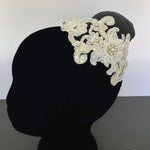 A side view of a white and cream headpiece displayed on a model.