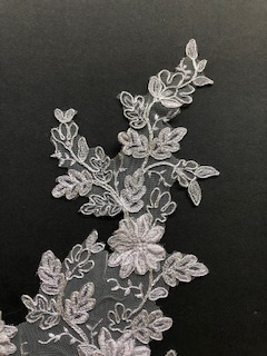 The applique is embrodered in an open floral deign allowing the base fabric to show through.smaller grey flowers Grey floral applique embellished with 3D flowers.