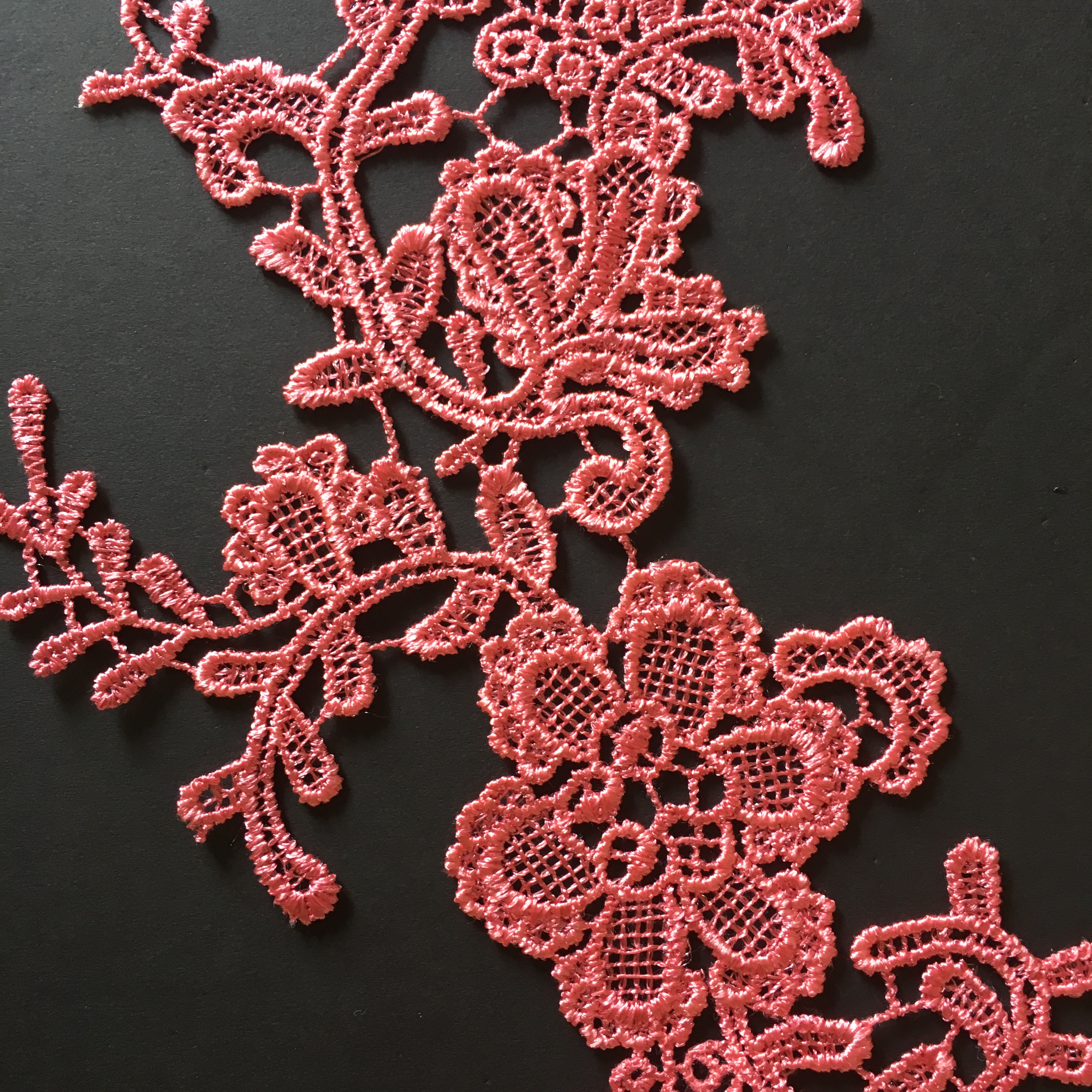 Close up view of watermelon pink embroidered floral lace applique.