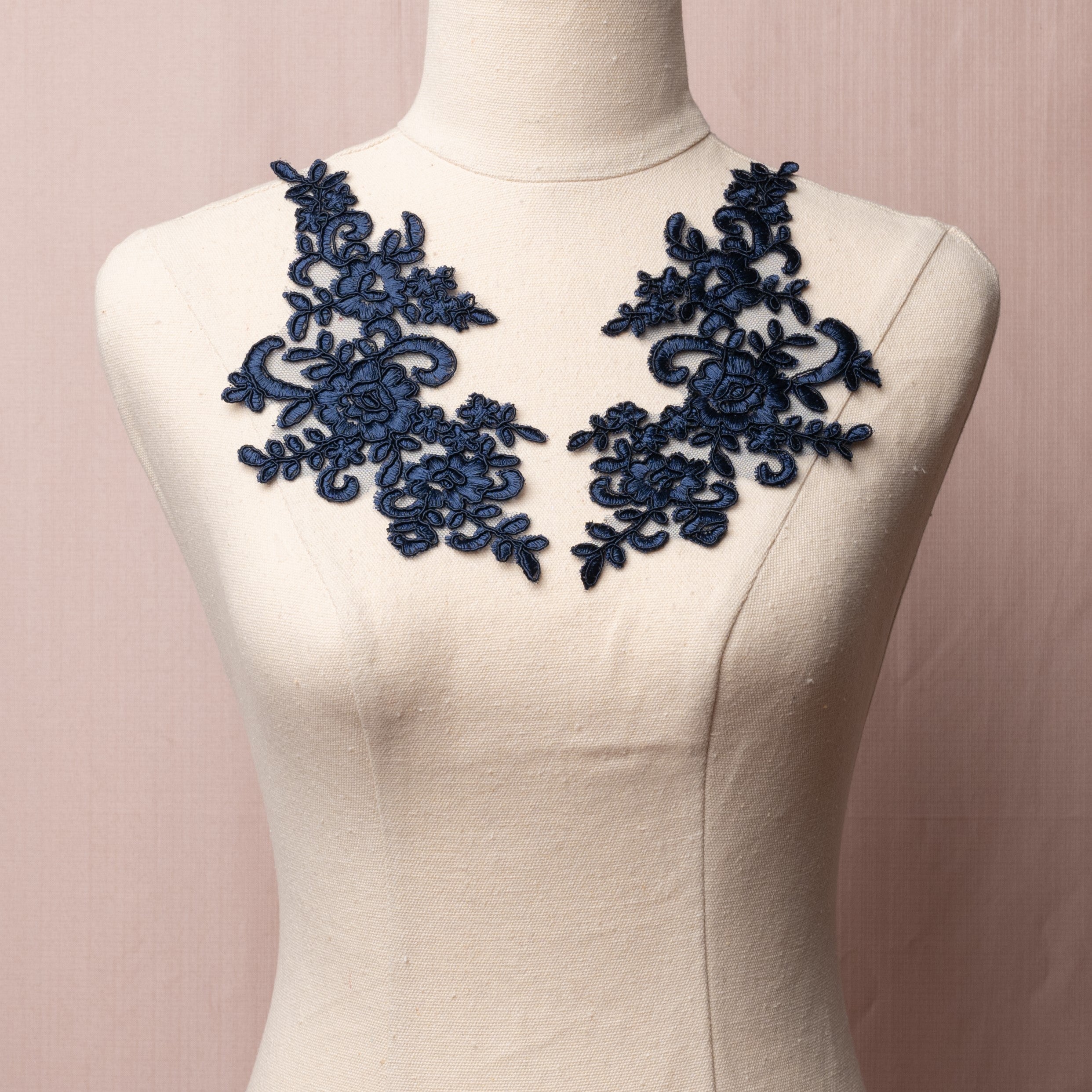 Navy blue embroidered floral applique with corded edging.  The applique is embroidered onto a net backing and displayed on a mannequin.