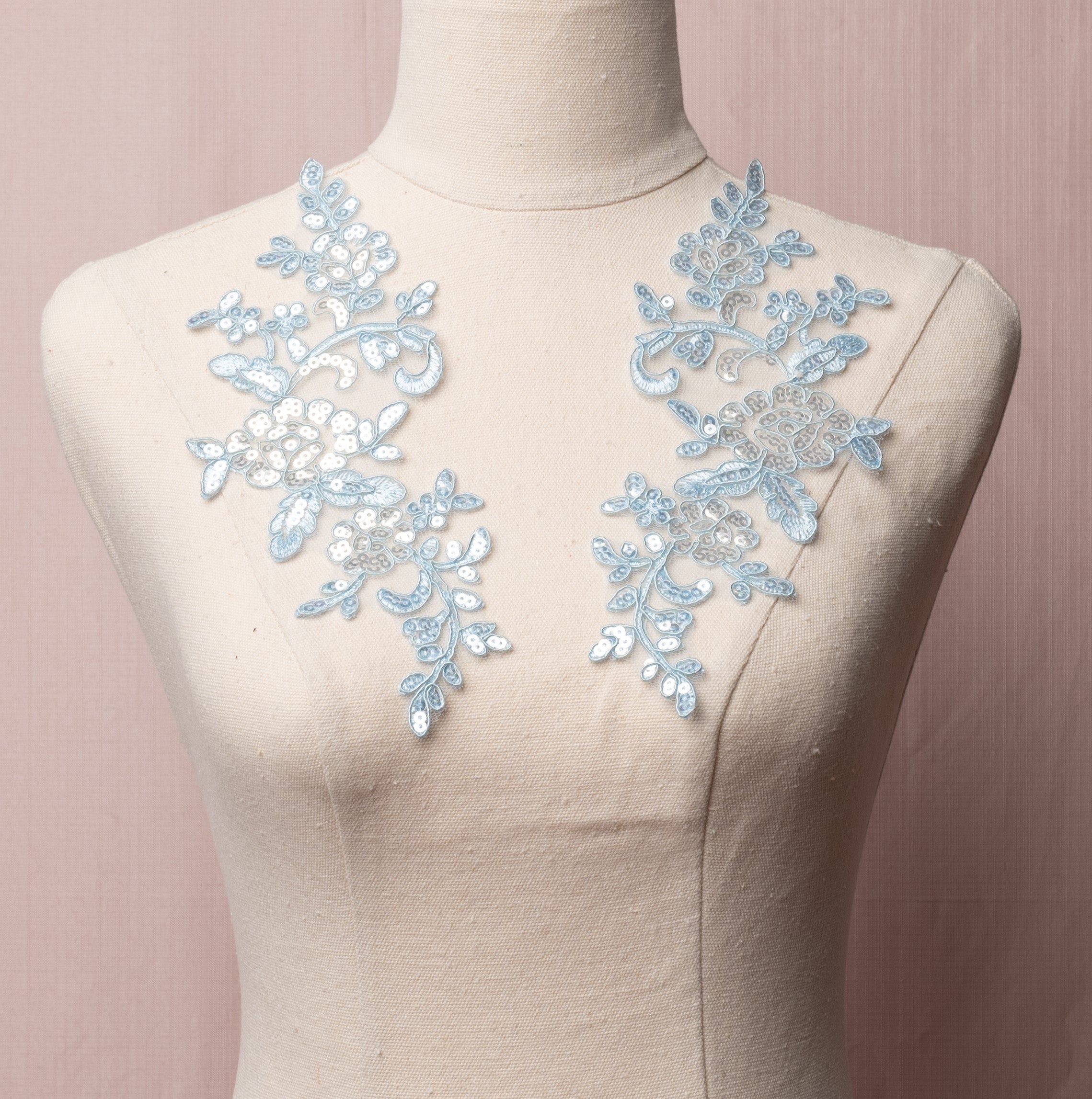 Pale blue embroidered and corded floral patterned applique pair covered with sequins.  The appliques are displayed on a mannequin.