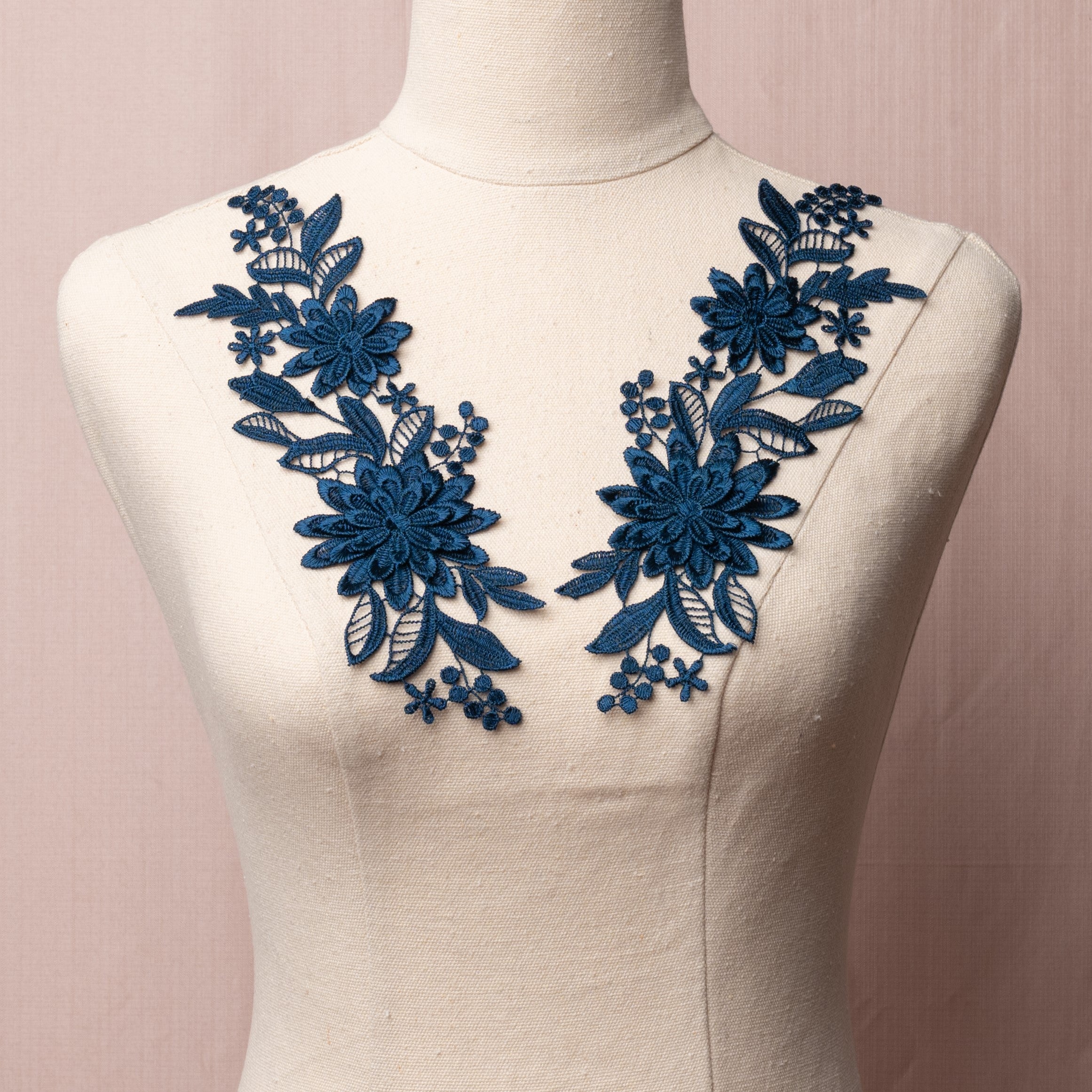Embroidered navy blue 3D lace applique pair displayed on a mannequin.