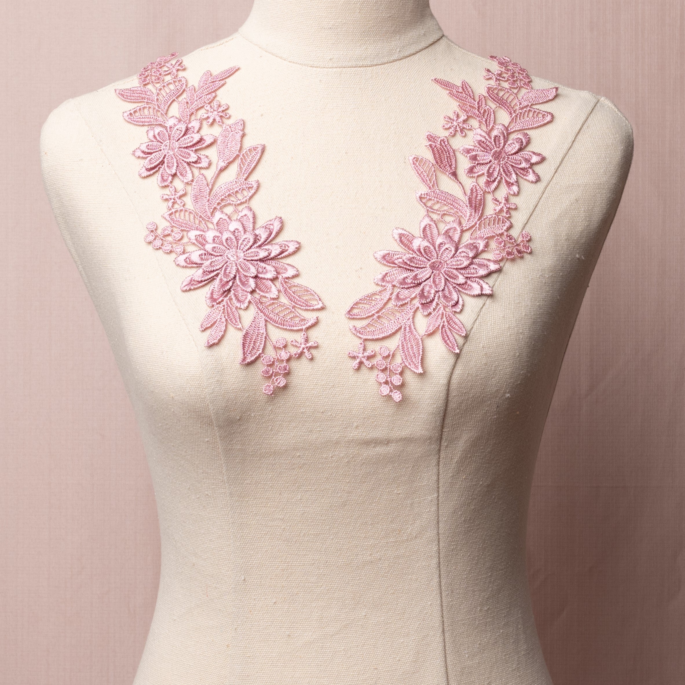 Embroidered dusty pink 3D lace applique pair with a floral design.  The larger flower shape has 3 layers of petals and the smaller flower shape has two layers of petals.  The appliques are displayed on a mannequin.