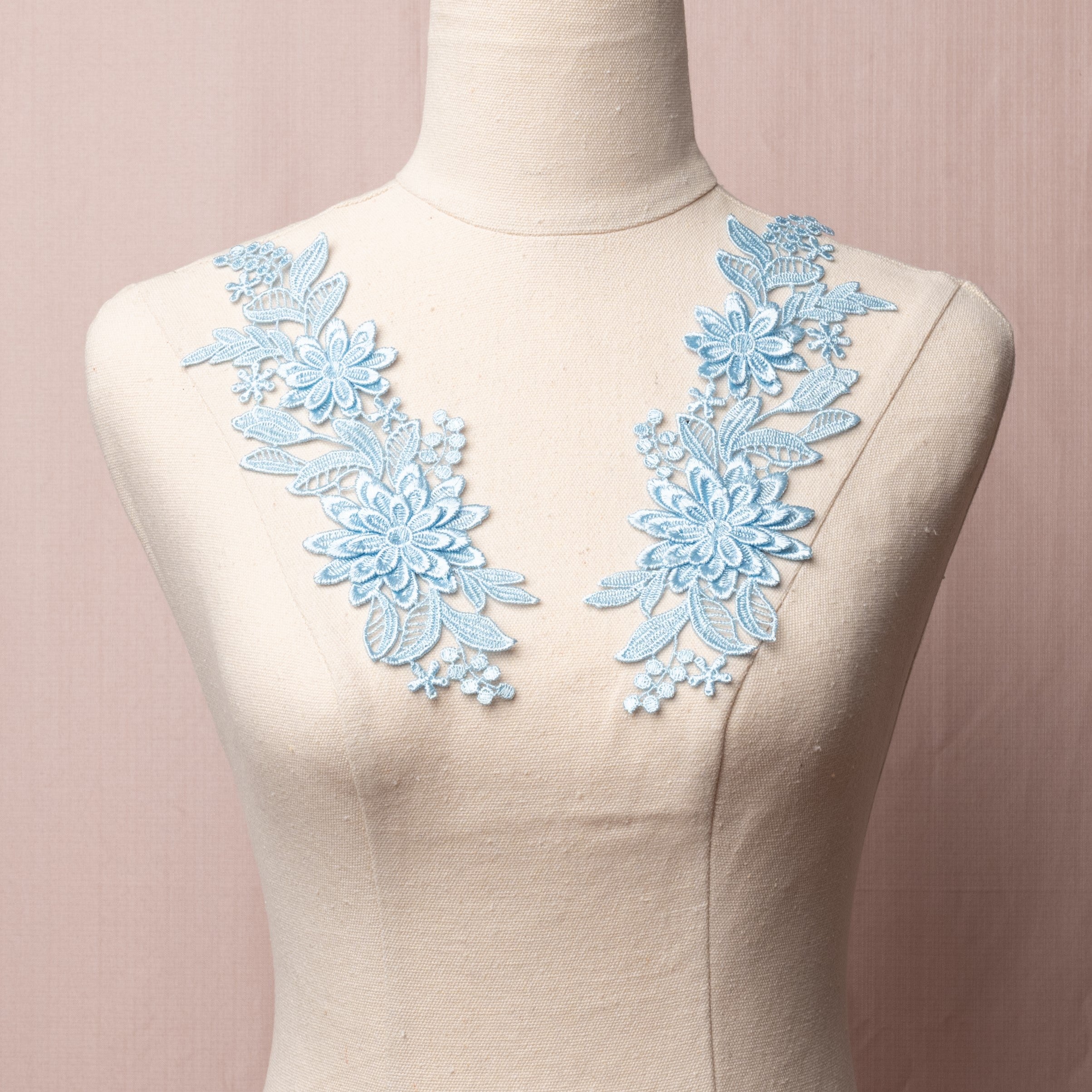 Baby blue lace applique with 3D flowers on an embroidered lace background. The appliques are displayed on a mannequin. 