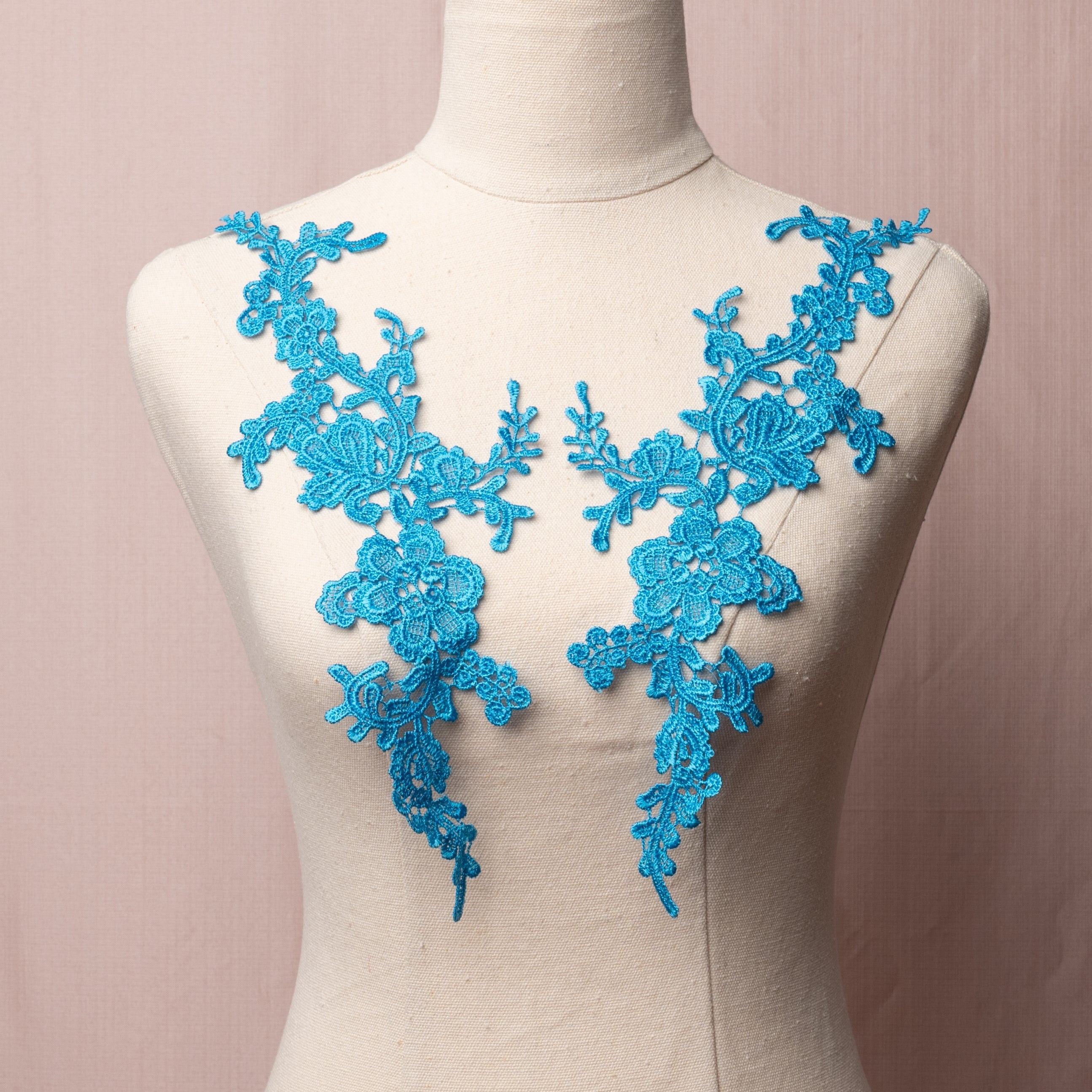 A bright blue applique pair embroidered in a lacy floral design displayed on a mannequin.