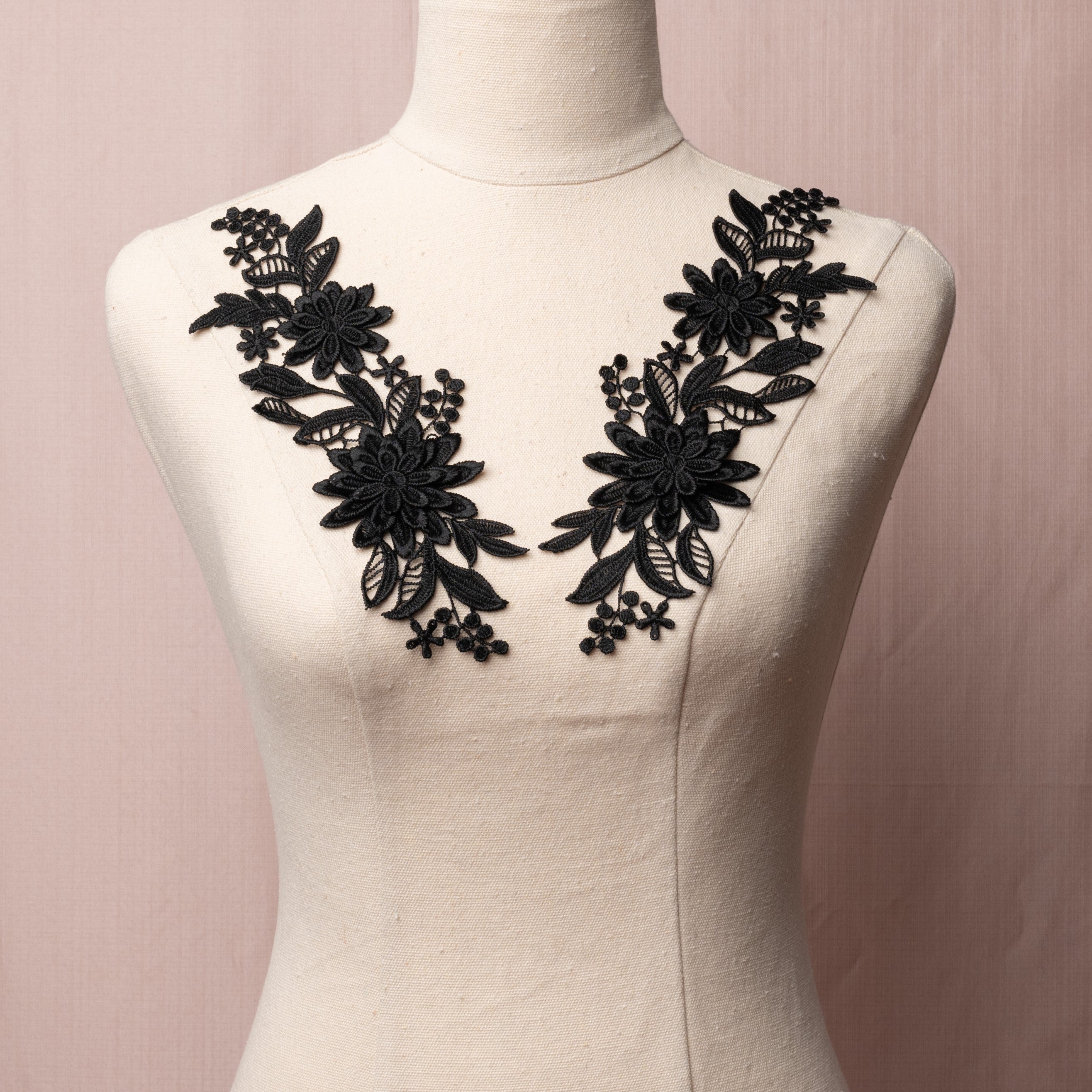 Embroidered black 3D lace applique pair displayed on a mannequin.