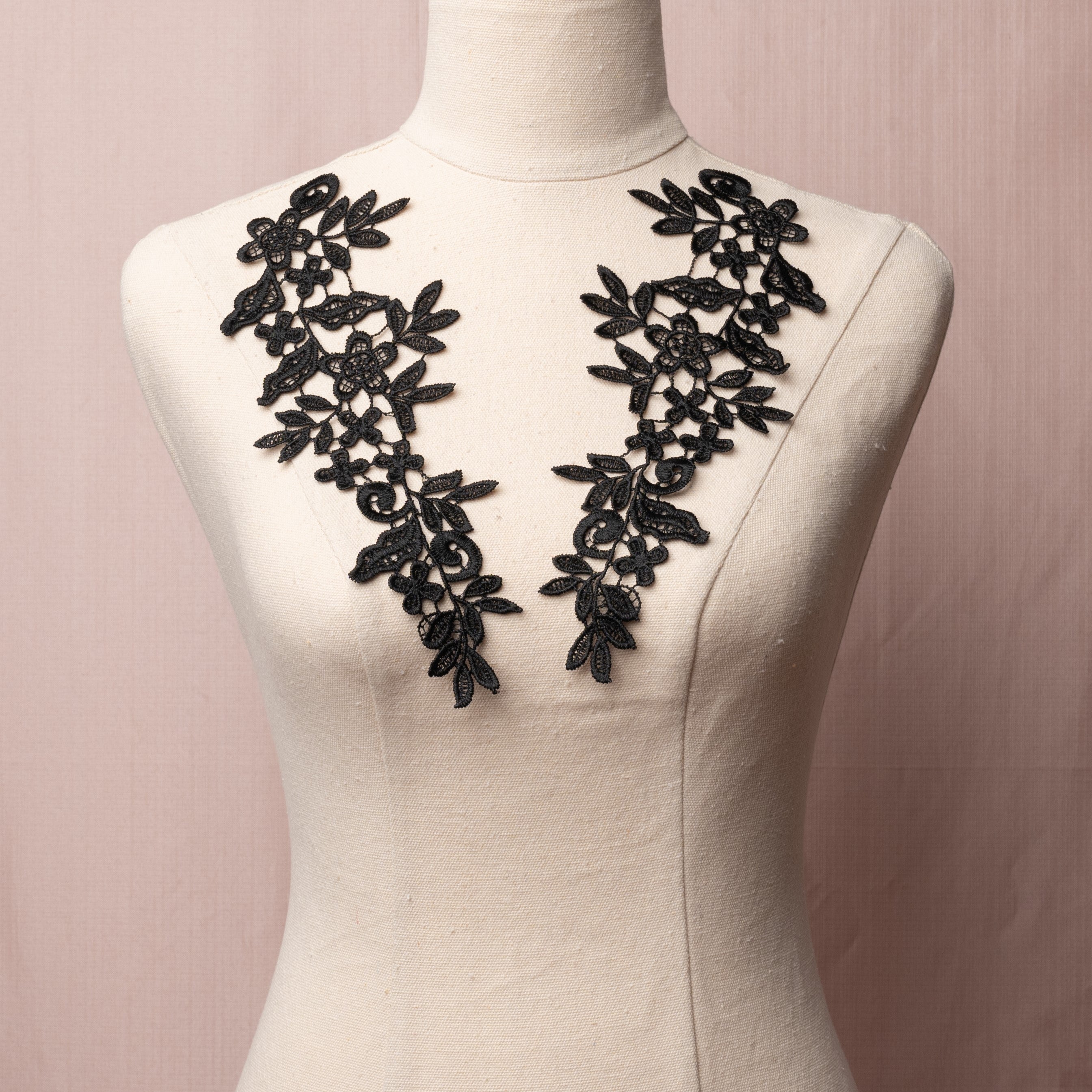 Heavily embroidered black mirrored lace applique pair displayed on a mannequin.