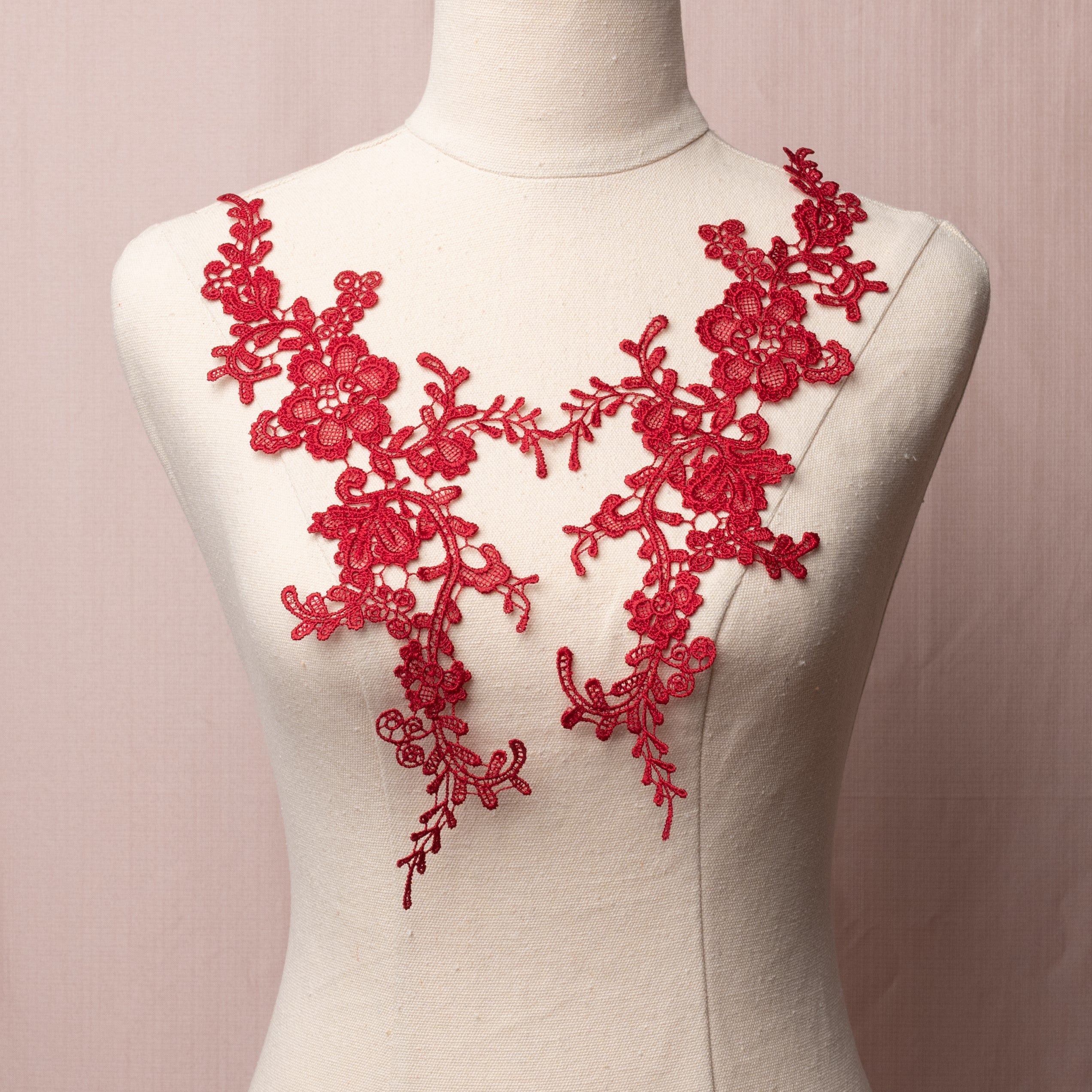 Heavily embroidered burgundy floral applique pair displayed on a mannequin.