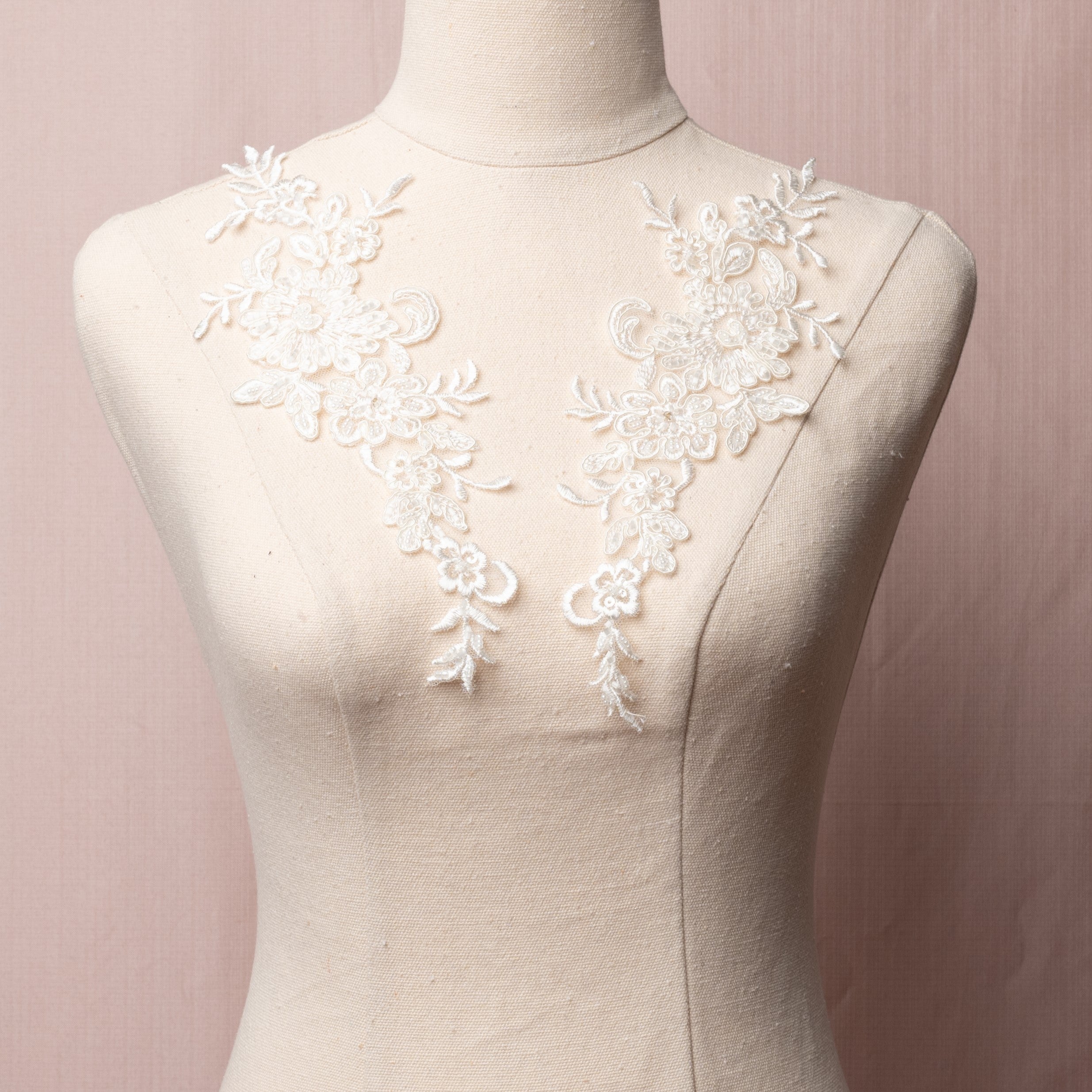 Cream beaded lace applique pair with a floral design displayed on a mannequin.