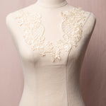 Deep cream floral embroidered and corded lace applique pair with cross hatch design in the centre of the applique.  The appliques are displayed on a mannequin.