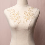 Cream embroidered floral applique pair with 3D flowers displayed on a mannequin.