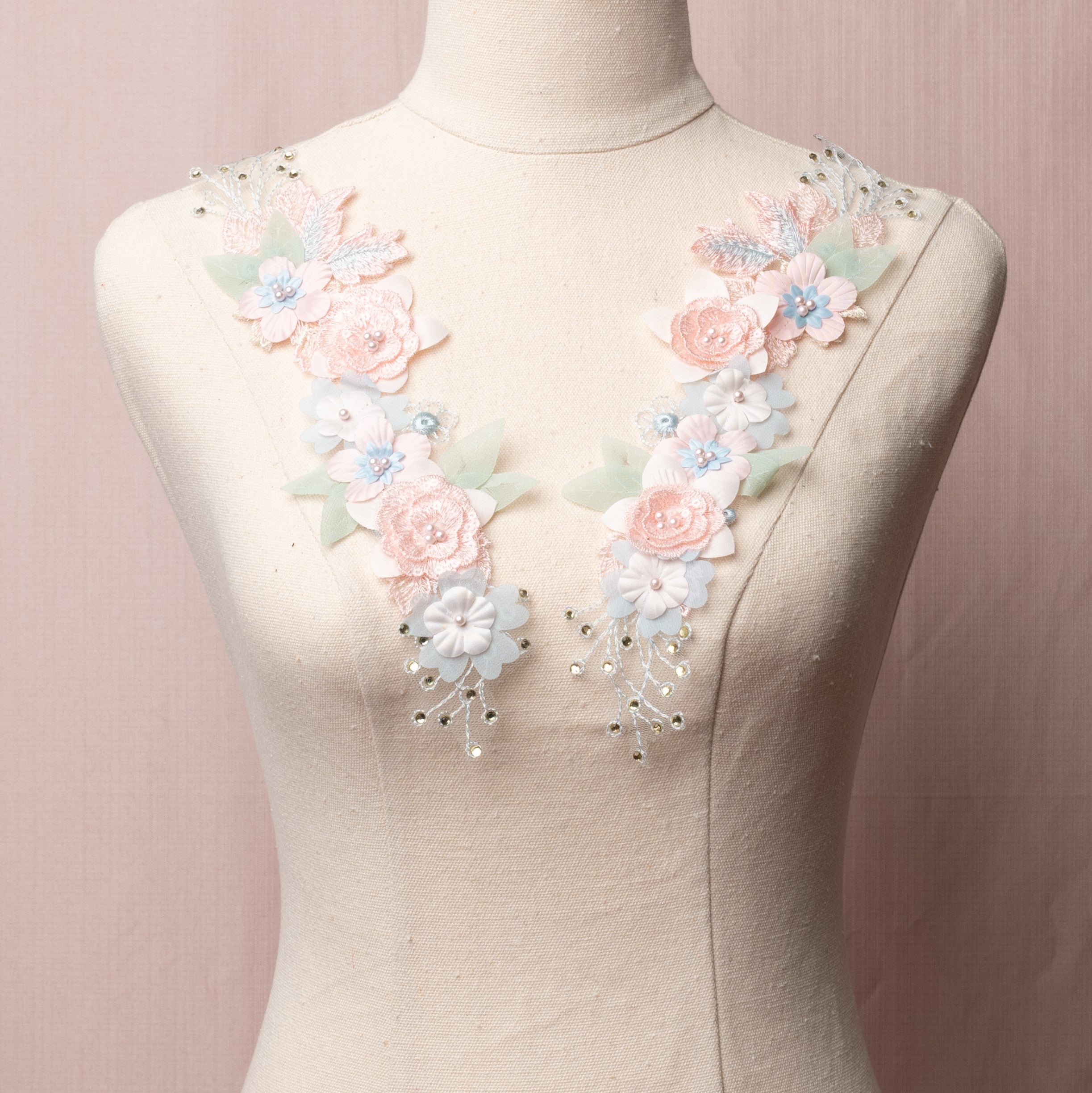 Pink, blue and sage green floral applique displayed on a mannequin.  The applique is decorated with gems and pearls.