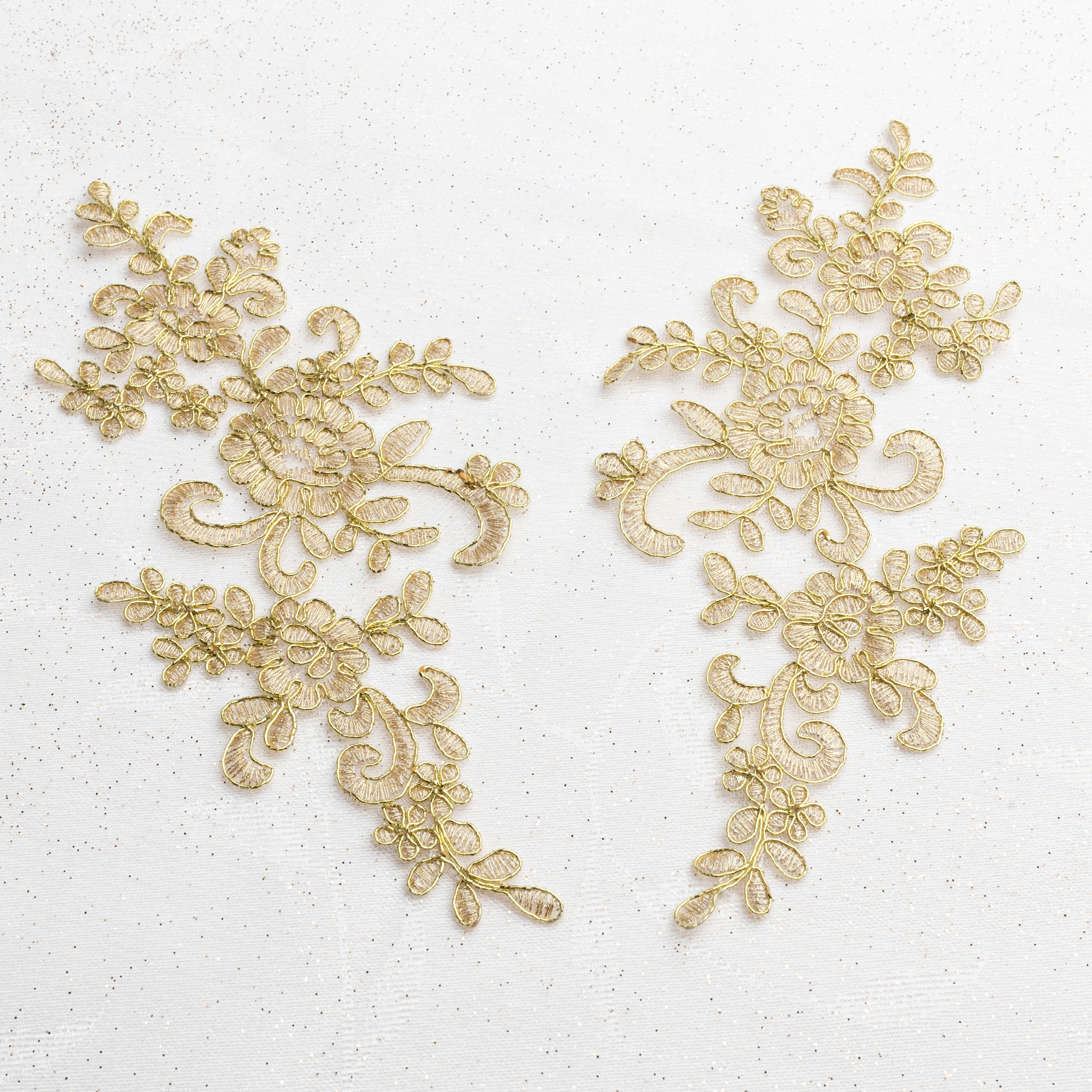 Mirrored pair of embroidered gold appliques edged with metallic gold cord. The appliques are laying flat on a white background.
