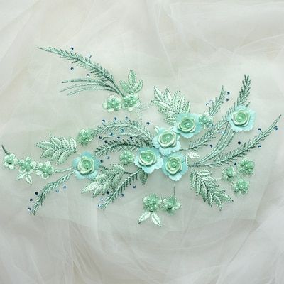 An embroidered floral spray applique with satin flowers and metallic threads.  The applique is laying flat on a white background.