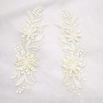 Embroidered ivory 3D lace applique pair with a floral design.  The larger flower shape has 3 layers of petals and the smaller flower shape has two layers of petals.  The applique is laying flat on a white background.   