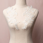 White floral applique embroidered with sparkly eye lash glitter thread.  The appliques are displayed on a mannequin.