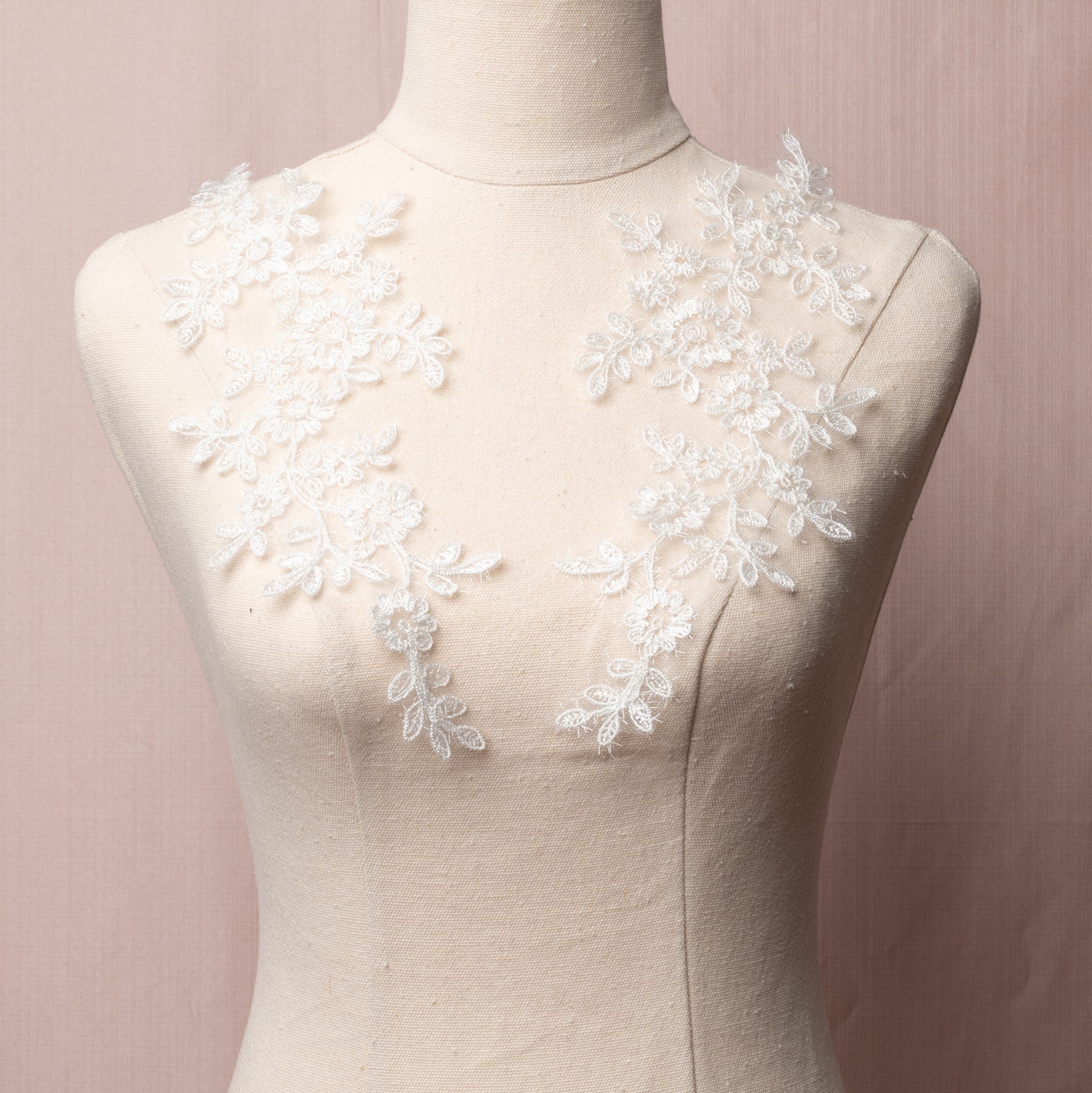 White floral applique embroidered with sparkly eye lash glitter thread.  The appliques are displayed on a mannequin.