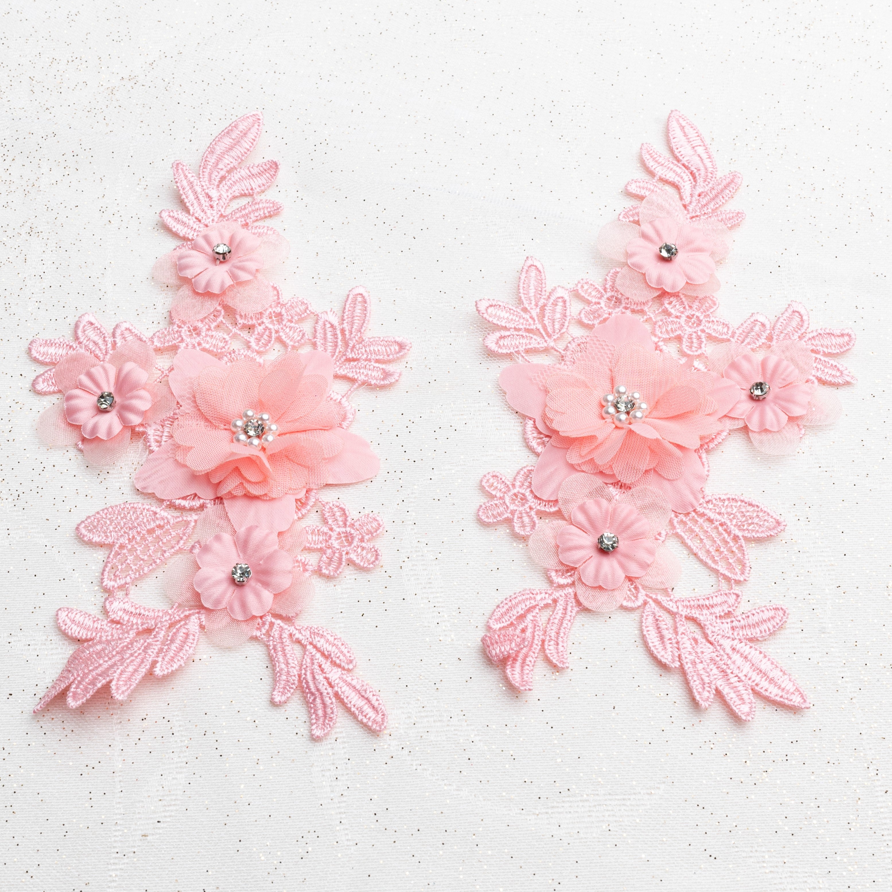 Pink applique pair embellished with 3D organza fabric flowers.  Flowers have a pearl and rhinestone centre.  The flowers are laying flat on a white background.