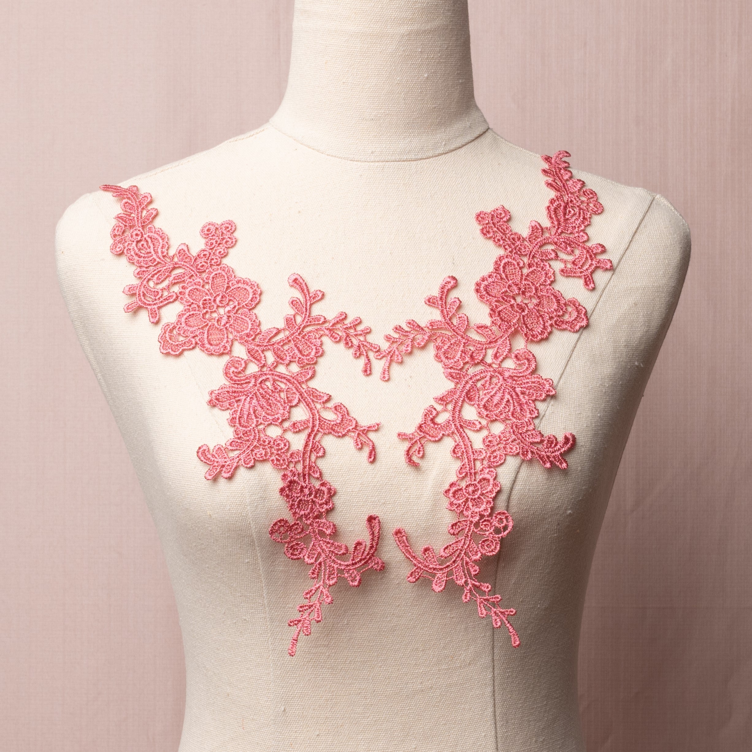 Watermelon pink lace applique pair embroidered with a flower pattern and displayed on a mannequin.
