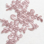 Close up of mushroom pink embroidered floral applique laying on a white background. 