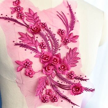 A pink embroidered floral applique with a spray of satin and metallic threads.  The applique is displayed on a mannequin.